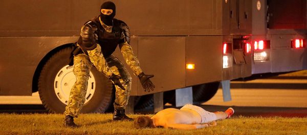 Сотрудник правоохранительных органов рядом с лежащим на земле протестующим во время столкновений после закрытия избирательных участков президентских выборов (9 августа 2020). Минск - Sputnik Армения
