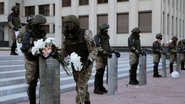 Военнослужащий внутренних войск МВД Беларуси несет цветы, оставленные демонстрантами во время демонстрации оппозиции в знак протеста против полицейского насилия и отказа от результатов президентских выборов (14 августа 2020). Минск - Sputnik Армения