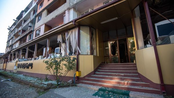 Вид на попавший под обстрел ВС Азербайджана жилой дом из окна пострадавшего мебельного магазина в Степанакерте, Карабах - Sputnik Армения