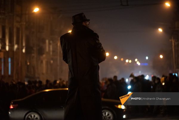 Мужчина в плаще следит за шествием оппозиции, требующих отставки правительства Армении (14 декабря 2020). Еревaн - Sputnik Армения