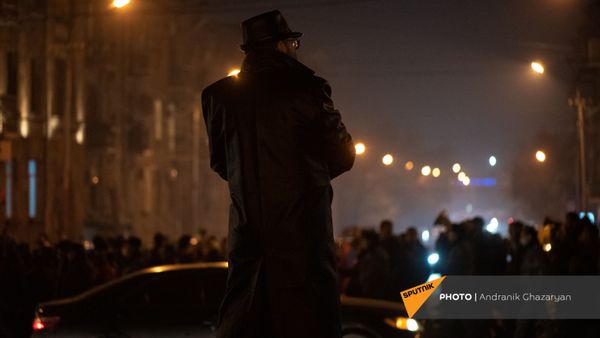 Мужчина в плаще следит за шествием оппозиции, требующих отставки правительства Армении (14 декабря 2020). Еревaн - Sputnik Армения