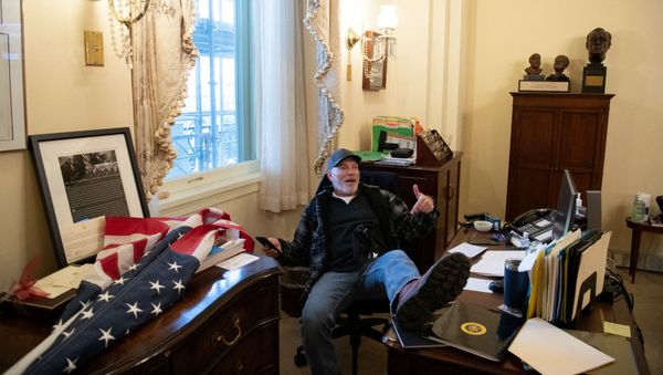 Cторонник президента США Дональда Трампа, Ричард Барнетт, сидит в кабинете спикера палаты представителей США Нэнси Пелоси во время акции протеста в Капитолии (6 декабря 2021). Вашингтон - Sputnik Армения