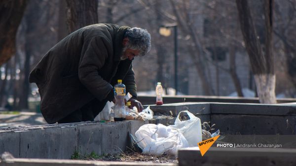 Бездомный мужчина обедает в городском парке - Sputnik Армения