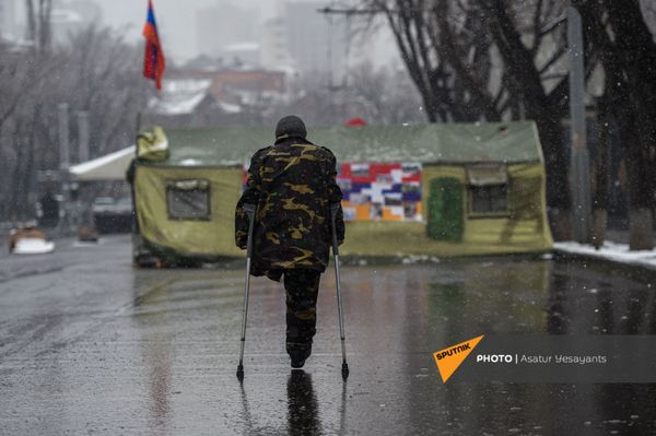 Ветеран войны с ампутированной ногой на фоне палаток, установленных на заблокированном оппозиционерами проспекте Баграмяна (1 марта 2021). Еревaн Ветеран войны с ампутированной ногой на фоне палаток, установленных на заблокированном оппозиционерами проспекте Баграмяна (1 марта 2021). Еревaн - Sputnik Армения