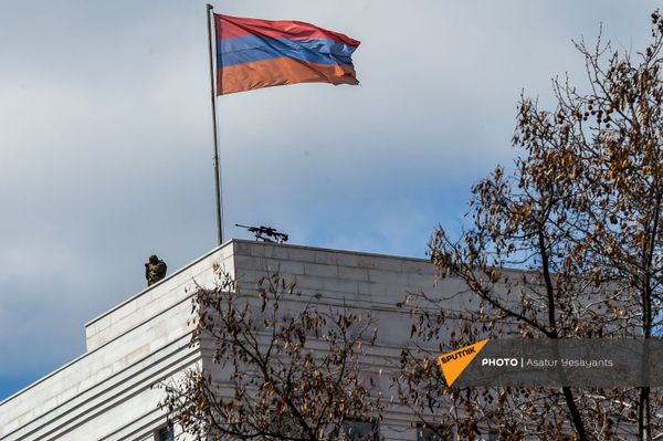 Сотрудник правоохранительных органов рядом с винтовкой на крыше здания МИД Армении (13 марта 2021). Еревaн - Sputnik Армения