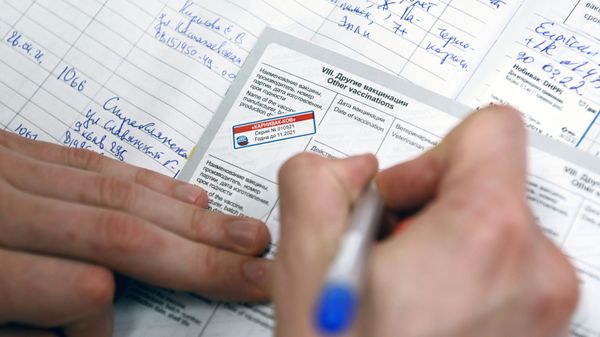 Ветеринарный врач делает отметку в паспорте животного после вакцинации от COVID-19 в ветеринарной клинике в Москве - Sputnik Армения