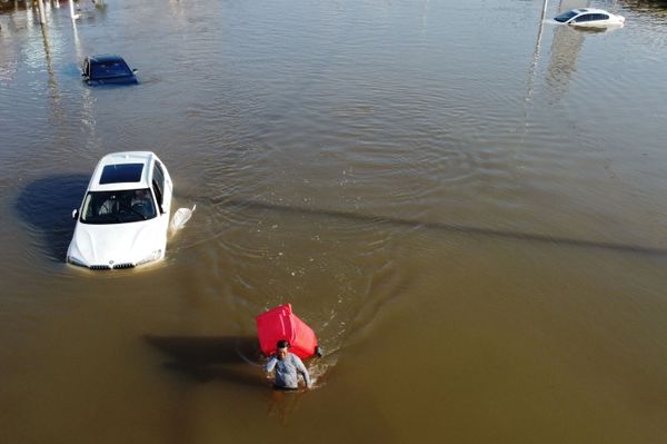 Мужчина с мусорным баком пробирается через паводковые воды после сильного дождя в деревне в Синьсяне, провинция Хэнань, Китай - Sputnik Армения