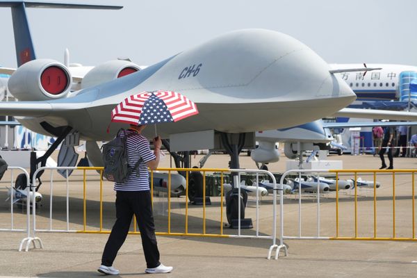 Мужчина с зонтом в цветах флага США у беспилотника CH-6 на Airshow China в Чжухае, Китай. - Sputnik Армения