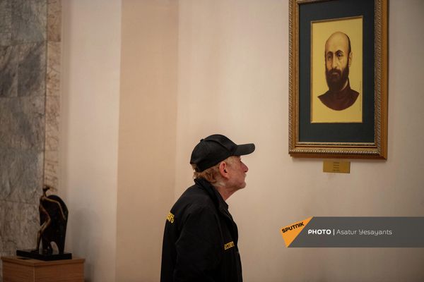 Сотрудник службы охраны Национального академического театра оперы и балета им. Спендиарова рассматривает портрет Комитаса. - Sputnik Армения