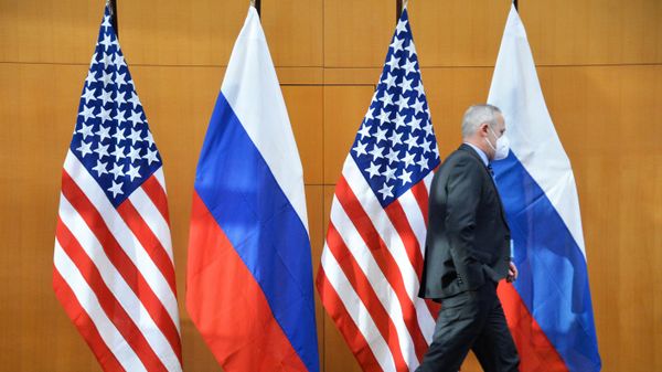 Мужчина проходит мимо флагов во время двусторонних переговоров по безопасности между США и Россией в Женеве. - Sputnik Армения