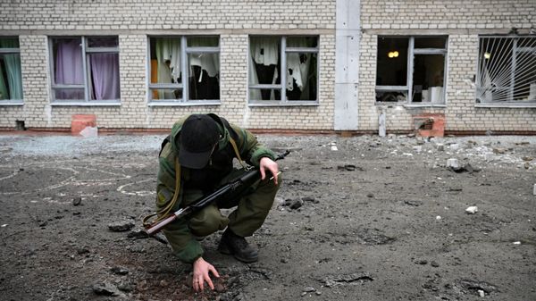 Сотрудник народной милиции ДНР возле воронки от снаряда у школы Горловки - Sputnik Армения