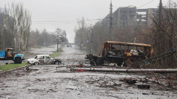 Разбитые автомобили на фоне сгоревших домов в Мариуполе (13 апреля 2022). Украина - Sputnik Армения