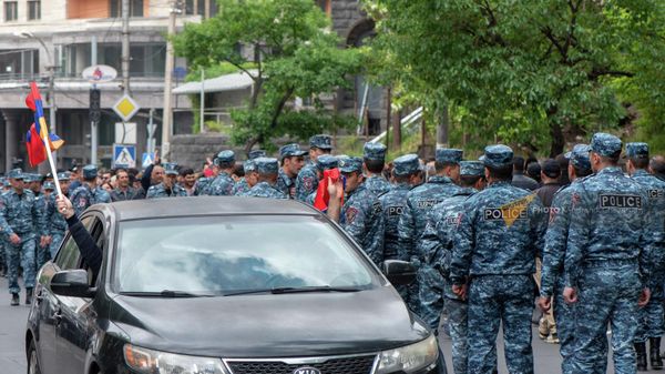 Автомобиль с флагами Армении и Арцаха проезжает мимо сопровождающих шествие сотрудников полиции на улице Сарьяна (3 мая 2022). Еревaн - Sputnik Армения