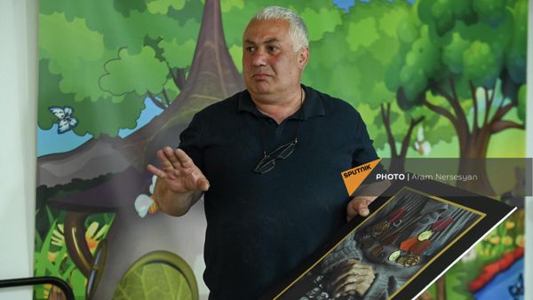 Фотограф Акоп Погосян показывает плакат выставки портретов ветеранов Великой Отечественной войны - Sputnik Армения