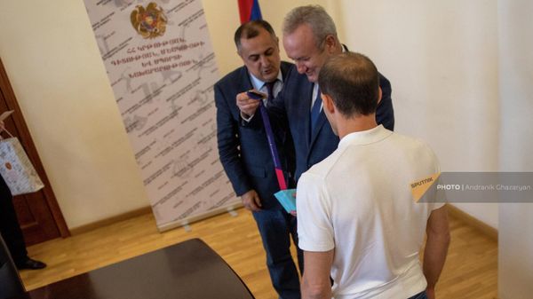 Министр ОНКС Ваграм Думанян и заместитель министра Карен Гилоян рассматривают медаль гимнаста Арутюна Мердиняна во время встречи (25 августа 2022). Еревaн - Sputnik Армения
