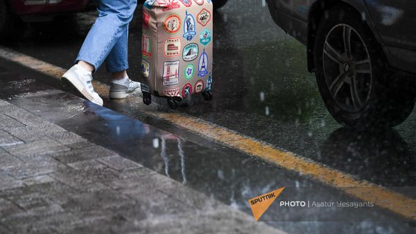 Женщина с чемоданом под дождем на одной улиц в Ереване - Sputnik Армения