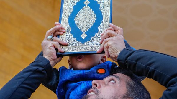 Мальчик целует Коран во время акции протеста с сожжением флагов Швеции и Нидерландов у мечети Мохаммеда аль-Амина (27 января 2023). Бейрут - Sputnik Армения