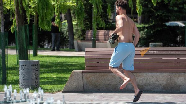 Молодой человек прыгает на одной ноге, обжегшись на горячей плитке городского парка (10 августа 2023). Еревaн - Sputnik Армения