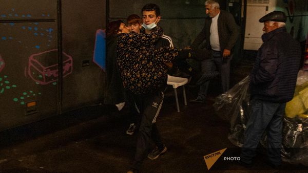 Волонтер Армянского общества Красного Креста несет на руках бабушку-инвалида - Sputnik Армения