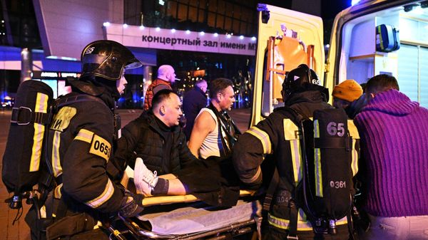 Сотрудники скорой помощи оказывают помощь пострадавшей у концертного зала Крокус Сити Холл в Москве, где произошла стрельба (22 марта 2024). Москва - Sputnik Армения