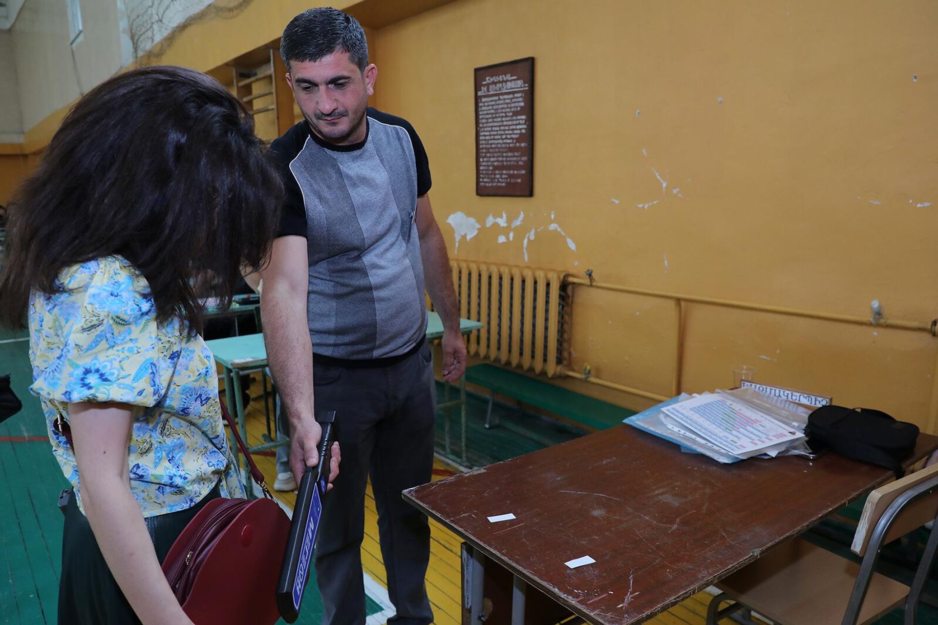 Член приемной комиссии проверяет выпускницу металлодетектором перед началом единого экзамена по предмету химия (11 июня 2024). Еревaн - Sputnik Արմենիա, 1920, 11.06.2024