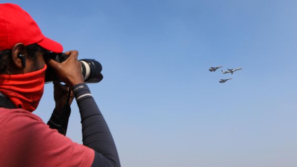 Фотограф снимает полет многоцелевых истребителей Су-30 и самолета дальнего радиолокационного обнаружения и управления ERJ-145I NETRA ВВС Индии на Aero India 2025  - Sputnik Армения