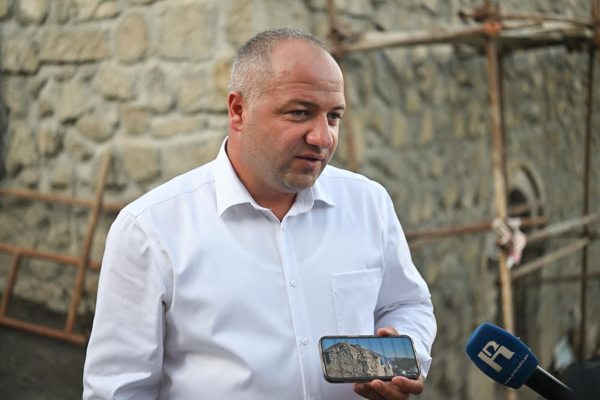 Директор ГНКО Служба по охране исторической среды и историко-культурных музеев-заповедников МОНКС РА Армен Ованнисян показывает фотографии церкви до реставрации - Sputnik Արմենիա, 1920, 27.08.2025