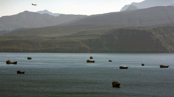 Самолет пролетает над горами к югу от Ормузского пролива, в то время как торговые корабли пришвартованы в водах Персидского залива недалеко от города Хасаб в Омане - Sputnik Армения