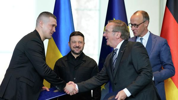Канцлер Германии Фридрих Мерц и президент Украины Владимир Зеленский наблюдают за тем, как министр обороны Украины Михаил Федоров пожимает руку министру обороны Германии Борису Писториусу во время церемонии подписания соглашения в рамках германо-украинских правительственных консультаций (14 апреля 2026). Киев - Sputnik Армения