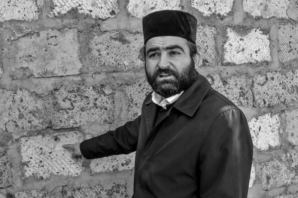Иерей Арам Мирзоян показывает стену из туфа рядом со школой, поврежденную стрельбой со стороны Азербайджана Иерей Арам Мирзоян показывает стену из туфа рядом со школой, поврежденную стрельбой со стороны Азербайджана - Sputnik Армения