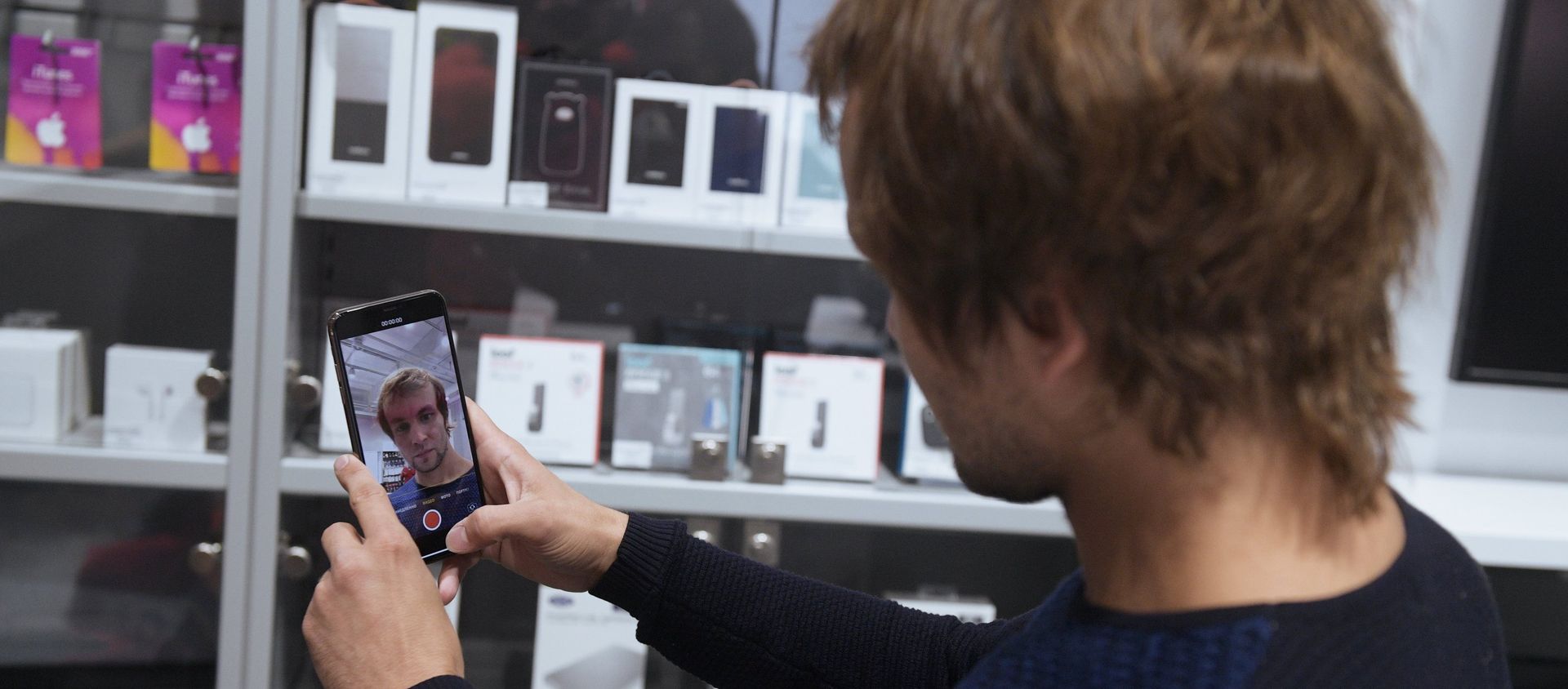 Мужчина рассматривает телефон iPhone XS Max в магазине re:Store (28 сентября 2018). Санкт-Петербург - Sputnik Արմենիա, 1920, 15.09.2019