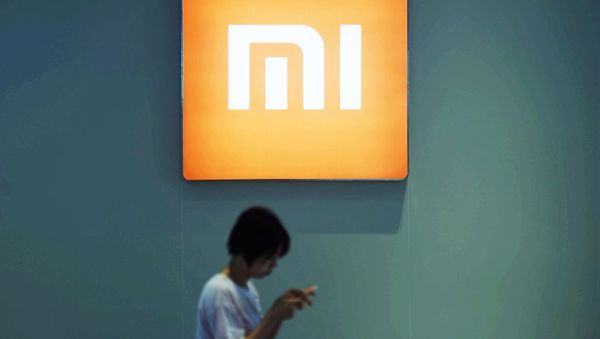 Пользоователь со смартфоном около логотипа Xiaomi - Sputnik Армения