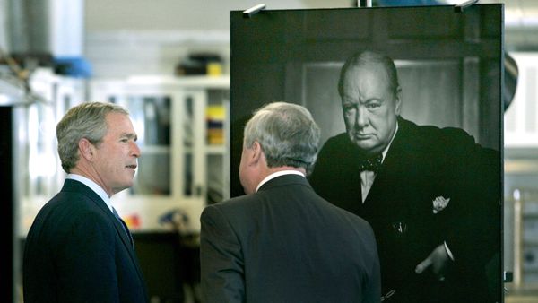 Президент США Джордж Буш-младший у портрета бывшего премьер-министра Великобритании Уинстона Черчилля фотографa Юсуфa Каршa во время экскурсии по Национальному центру сохранения архивов (30 ноября 2004). Оттавa - Sputnik Армения