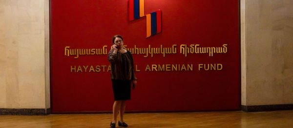 Женщина с телефоном у логотипа Всеармянского фонда Айастан - Sputnik Արմենիա