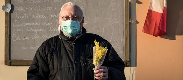 Жизнь в красной зоне: человек в защитной маске держит букет цветов на улице на 16-й день карантина в Сан-Фьорано, одном из 11 небольших городов на севере Италии, который был заблокирован с февраля (7 марта 2020). Италия - Sputnik Армения