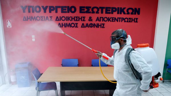 Рабочий в защитном костюме дезинфицирует офис гражданской службы в восточном пригороде Афин Дафни (9 марта 2020). Греция - Sputnik Армения