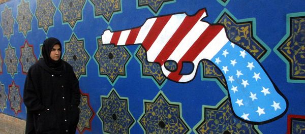Женщина проходит мимо бывшего здания посольства США в Иране, на стене которого нарисован револьвер цветами американского флага Женщина проходит мимо бывшего здания посольства США в Иране, на стене которого нарисован револьвер цветами американского флага - Sputnik Армения